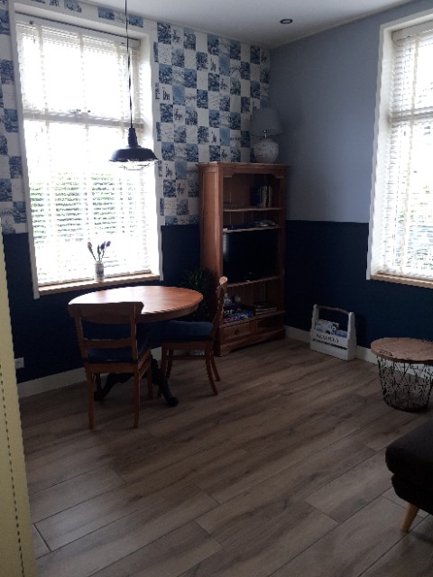 Foto met ronde houten tafel. boekenkast en ramen