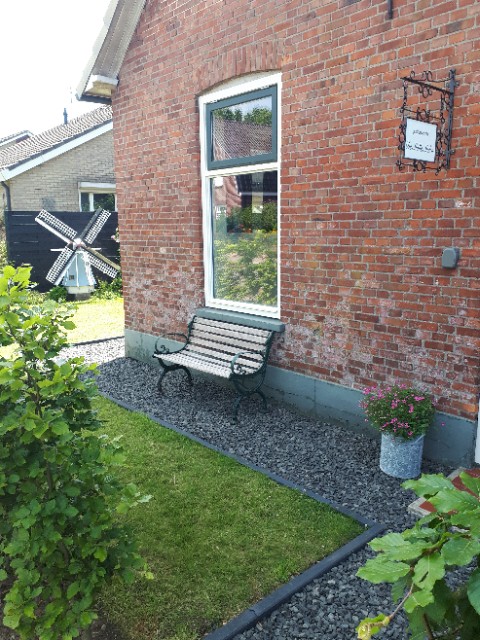 buitenzijde pand met bankje vor raam en molen op de achtergrond